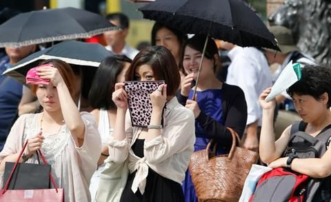People carrying umbrellas and handkerchiefs to protect themselves from the scotching sun